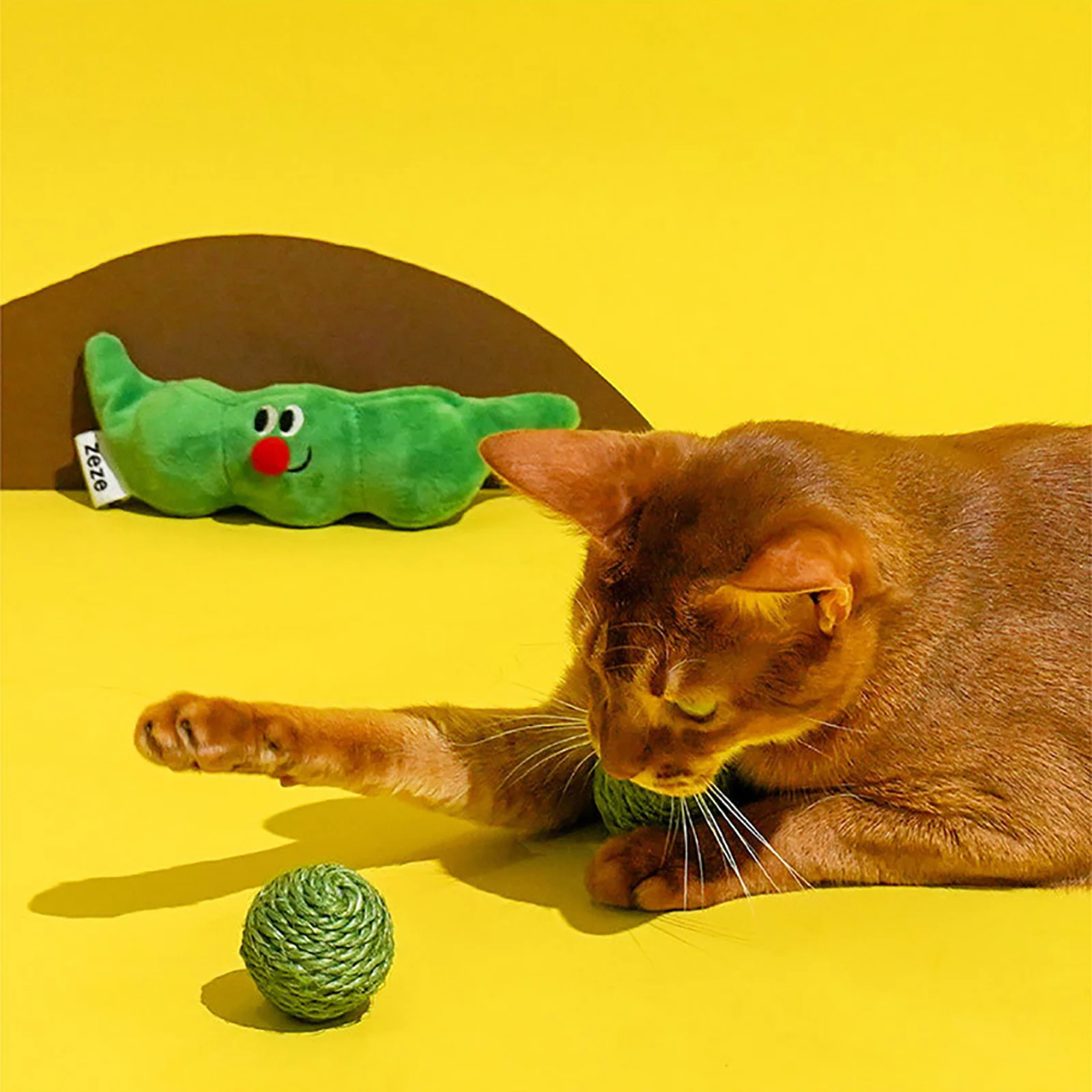Ginger cat reaching for a sisal toy ball