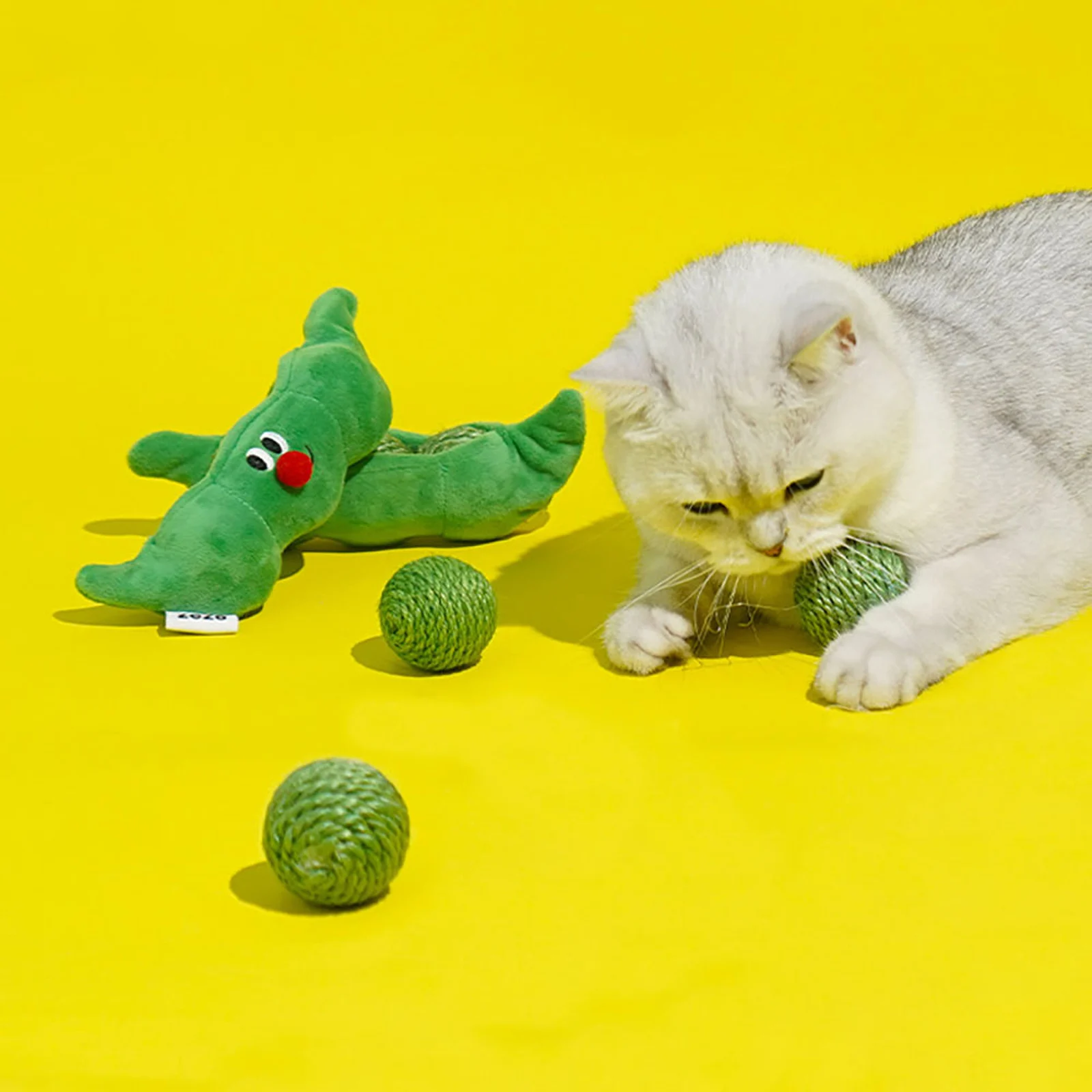 White cat playing with sisal toy balls